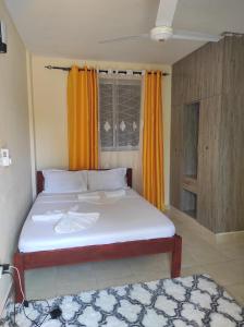 a bedroom with a large bed with orange curtains at GCG STAYS ltd in Mtwapa