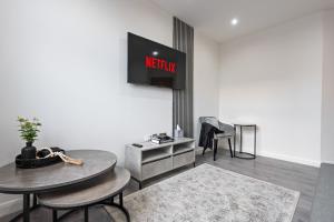 a living room with a table and a tv on the wall at The Emerald Residence - Leicester - City Centre, Sofa Bed, Parking, Free WiFi, Netflix in Leicester +46 photos