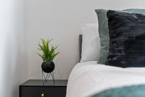 a plant on a night stand next to a bed at The Emerald Residence - Leicester - City Centre, Sofa Bed, Parking, Free WiFi, Netflix in Leicester