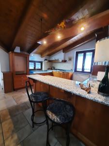 a large kitchen with a counter and two chairs at Casa Vacanza Dal Contadino in Corteno Golgi