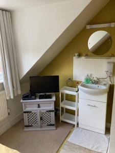 a bathroom with a sink and a television in a attic at House on the Corner B&B in Didcot