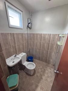 a bathroom with a toilet and a sink and a window at Eme's Apartelle in General Luna