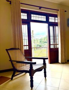 a chair in front of a large window with a balcony at The Kandy City Townhouse in Kandy