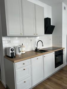 a kitchen with white cabinets and a sink at Apartament Parkowa-prywatny parking in Olecko