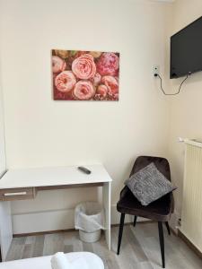 a room with a desk and a chair with a picture of roses at Hôtel Le Square in Capvern