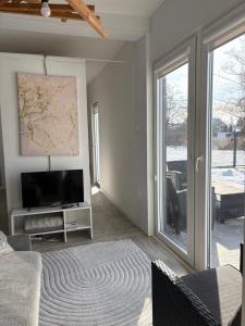 a living room with a tv and sliding glass doors at Domek nad Strugą przy stawach 10 km od Warszawy" Jacuzzi na zamówienie" in Halinow