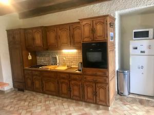 a kitchen with wooden cabinets and a sink and a refrigerator at La Ville de Mainguy in Josselin