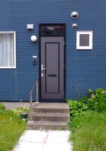 a blue house with a blue door and stairs at Guest House Annabel in Hakodate