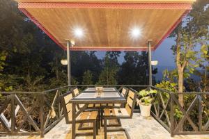 a table and chairs on a patio with a view at River and Roots Resort, Riverside Boutique Stay , Bonfire, Scenic Views in Dehradun
