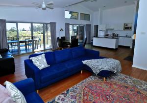 a living room with a blue couch and a kitchen at Beltana Villas in Pokolbin