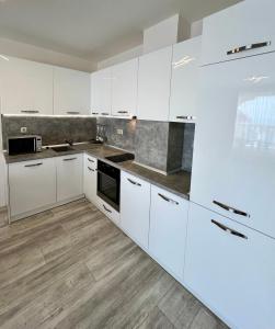 a white kitchen with white cabinets and wooden floors at La Mer Prime Time in Varna City