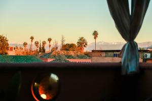 a window with a view of palm trees and mountains at Riad Allal in Marrakesh