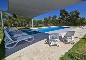 a group of lawn chairs sitting next to a swimming pool at Beltana Villas in Pokolbin