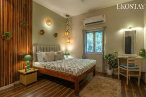 a bedroom with a bed and a desk and a window at EKOSTAY - Copacabana Villa in North goa