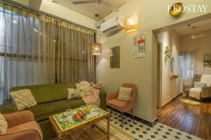a living room with a green couch and a table at EKOSTAY - Copacabana Villa in North goa +20 photos