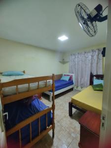 a room with three bunk beds and a fan at Aconchego famíliar in Mongaguá