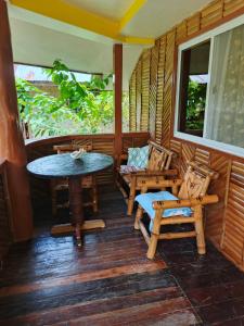 a porch of a house with a table and chairs at Greenviews Resort & Restaurant Port Barton in San Vicente