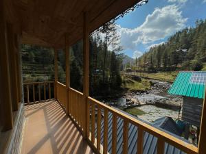 a balcony of a house with a view of a river at Alpine Stays Riverside in Jibhi