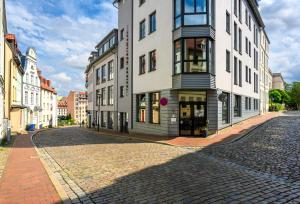 a building on a cobblestone street in a city at THE GREEN Rostock Apartment Hotel in Rostock
