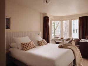 a bedroom with a large white bed and a window at Adam's Museum House in Amsterdam