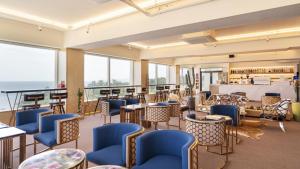 a restaurant with blue chairs and tables and windows at 온더웨이브호텔 in Taesong