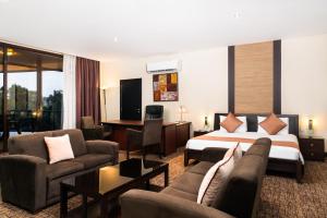 a hotel room with a bed and a couch and chairs at Hotel 33 Kampala in Kampala