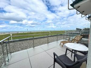 a balcony with a table and chairs and the beach at Strandvilla Therese Appartment 5 in Norderney