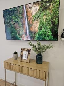 a painting hanging on a wall above a table with a plant at The Yellow Cottage in Lomba de São Pedro