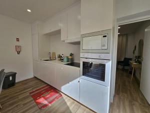 a kitchen with white cabinets and a stove top oven at The Yellow Cottage in Lomba de São Pedro