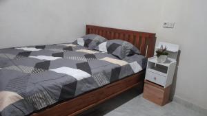 a bed with black and white comforter and a night stand at Bali Home Taksu in Jatiluwih