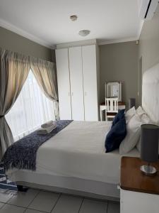 a bedroom with a large white bed with a window at Nine On Borghorst in Port Elizabeth