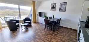 a living room with a table and chairs and a kitchen at Boddenhof Apartment 56 - 2 SZ, freundlich, modern in Buschvitz