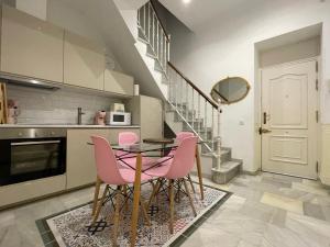a kitchen with a glass table and pink chairs at La Casa de María Castaña in Seville