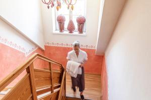 an older woman walking down a staircase in a house at Zum Kirchenwirt in Anzing