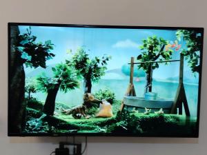 a television screen with a picture of a dog and trees at الرائد للشقق المفروشة in Amman