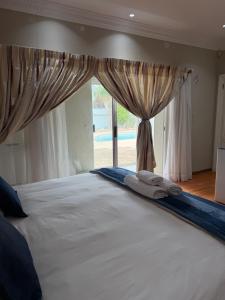 a bedroom with a large white bed with a window at Nine On Borghorst in Port Elizabeth
