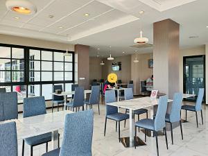 a restaurant with tables and chairs and a person in the background at โคโค่ โฮเทล KOCO Hotel in Nakhon Ratchasima