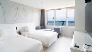 a hotel room with two beds and a view of the ocean at 온더웨이브호텔 in Taesong