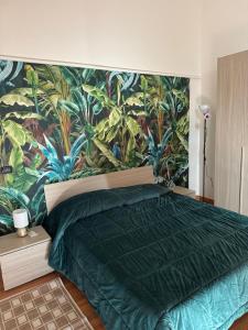 a bedroom with a green bed with a tropical wallpaper at SuiteMazzini in Lamezia Terme