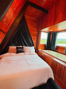 a bedroom with a bed with a window and a tub at Recanto Porto Chalé e SPA in Penha