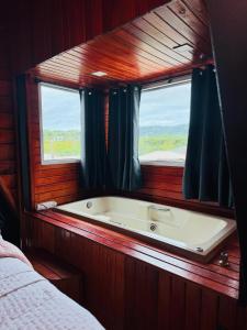 a bath tub in a room with a window at Recanto Porto Chalé e SPA in Penha