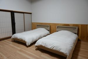 two beds with white covers in a room at 森ノ間 大谷荘 in Myoko