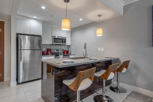 a kitchen with a bar with chairs and a refrigerator at Vibrant Stylish, Cozy Waterfront Downtown in Calgary