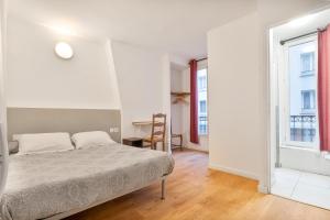 a white bedroom with a bed and a window at Hotel de Nantes in Paris
