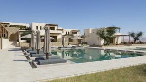 a swimming pool with umbrellas in front of a building at Agali Hotel Milos in Adamantas