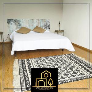 a bedroom with a white bed and a black and white rug at Casa do Alpendre in Arco de Baúlhe +18 photos