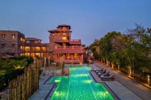 a swimming pool with green lights in front of a building at Seraibagh Ranthmabore in Khilchipur +34 photos