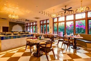 a dining room with tables and chairs and windows at Seraibagh Ranthmabore in Khilchipur