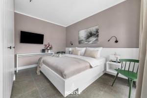 a white bedroom with a bed and a tv at Ferienwohnung TheViewB17 Boje 17 Dagebüll in Dagebüll