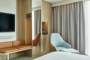 a hotel room with a bed and a chair and a tv at Courtyard by Marriott Sheffield in Sheffield
